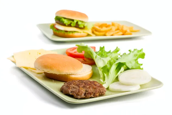 Cheeseburger and ingredients for another burger — Stock Photo, Image