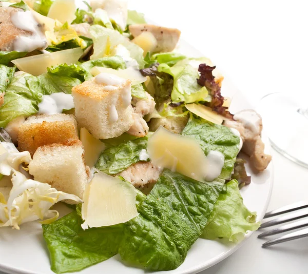 Traditional caesar salad on white plate with a fork — Stock Photo, Image