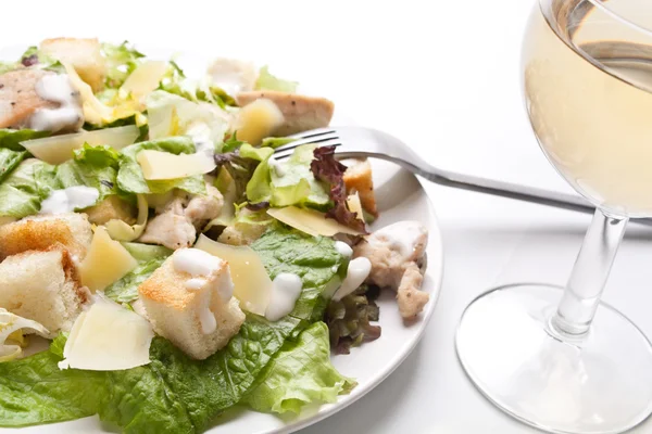 Salade césar traditionnelle avec un verre de vin blanc — Photo