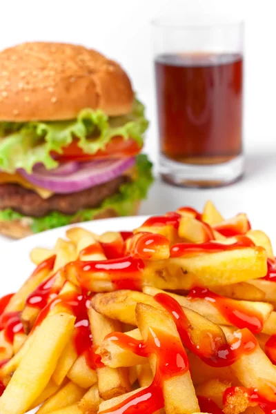 Papas fritas vertidas con mucho ketchup con una hamburguesa con queso y una cola — Foto de Stock