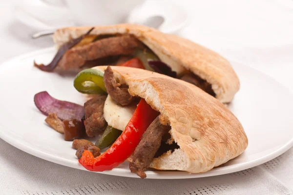 Två halvor av pitabröd smörgås med kött och grönsaker på en — Stockfoto