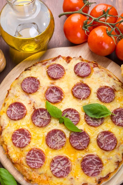 Pizza entera de salami en una tabla de cortar de madera — Foto de Stock