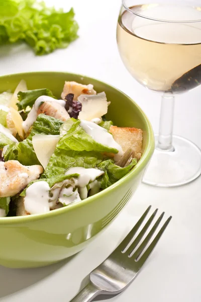 Salade césar traditionnelle avec un verre de vin blanc — Photo