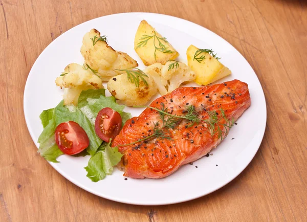 Тарілка зі смачним лососем, прикрашена овочами — стокове фото