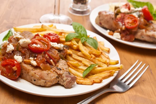 Dos porciones de chuletas de cerdo con tomate fresco, cebolla, ajo y — Foto de Stock