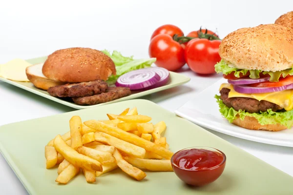 Two big cheeseburgers and french fries with tomatoes and ingredi — Stock Photo, Image