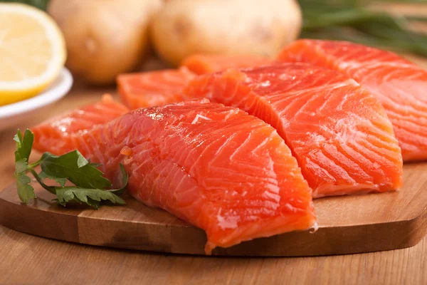 Tres trozos de salmón en una tabla de cortar — Foto de Stock