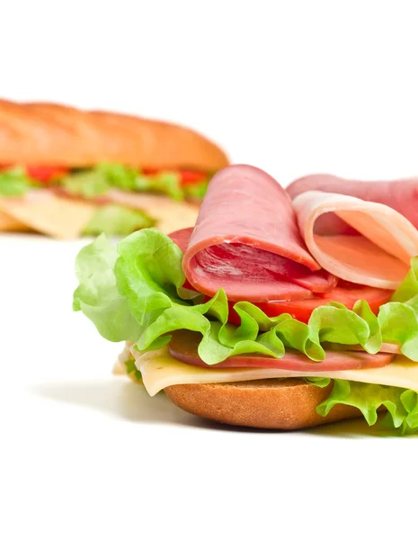 Two halves of long baguette sandwich with lettuce, tomatoes, ham — Stock Photo, Image