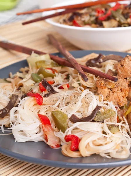 Rice noodles with vegetables, chicken and pair of chopsticks — Stock Photo, Image
