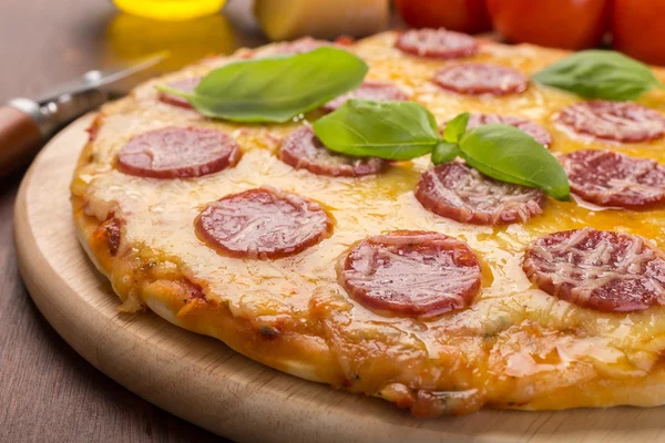 Whole salami pizza on a wooden cuttig board — Stock Photo, Image