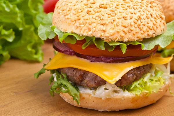 Big tasty  cheeseburger on a wooden table Royalty Free Stock Photos