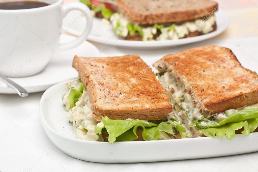 egg salad sandwiches on toasted bread and a cup of coffee