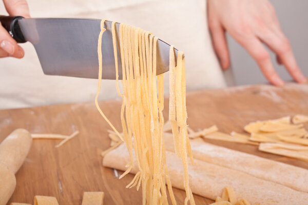 uncooked homemade egg pasta lifted up with a knife