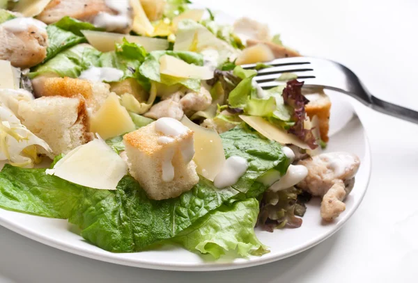 Traditional caesar salad on white plate with a fork — Stock Photo, Image