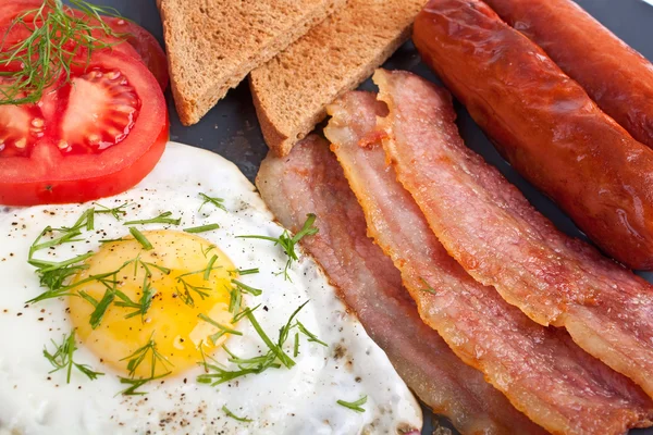 Ovos fritos, enchidos, bacon e torradas — Fotografia de Stock