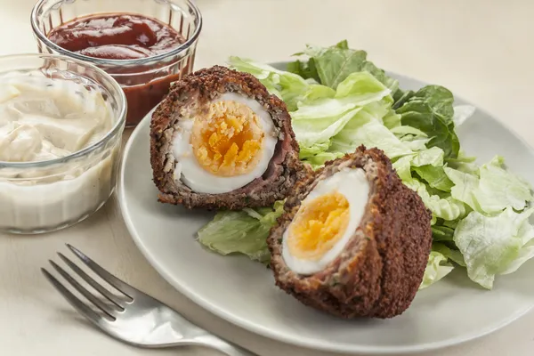 Scotch eggs cut in halves on a plate — Stock Photo, Image