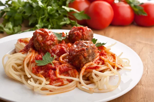 Спагетти с фрикадельками в томатном соусе на тарелке — стоковое фото