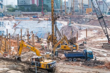 Kuala Lumpur, Malezya - 2 Temmuz 2018: Toprak taşıma yükleyicisi inşaat alanında çalışıyor, işçiler inşaat alanında çalışırken görülebiliyor.