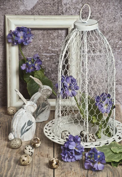 Easter eggs in a cage, spring blue  flowers, quail eggs, white bunnies  , white frame, white frame, wooden floor  nature — Stock Photo, Image