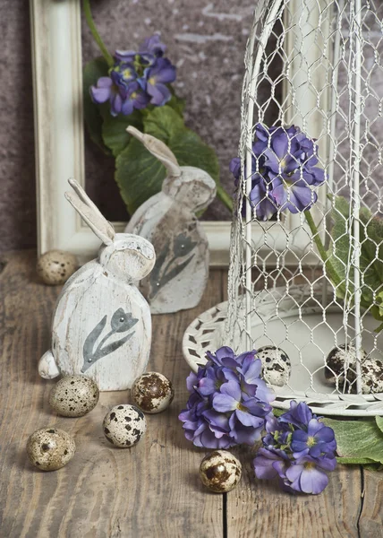 Easter eggs in a cage, spring blue  flowers, quail eggs, white bunnies  , white frame, white frame, wooden floor  nature — Stock Photo, Image