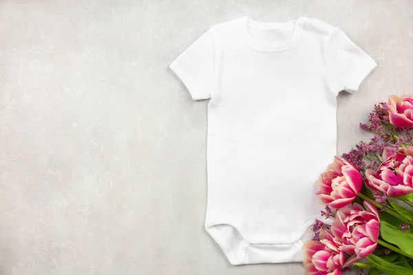 White baby girl or boy bodysuit mockup flat lay with tulip flowers on gray concrete background. Design onesie template, print presentation mock up. Top view. — 스톡 사진
