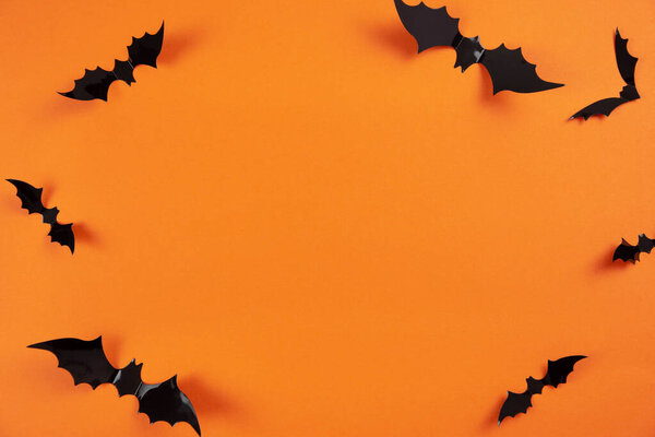 Счастливый плоский Хэллоуин с черными летучими мышами на оранжевом фоне. Концепция праздника. Вид сверху. Копирование пространства.