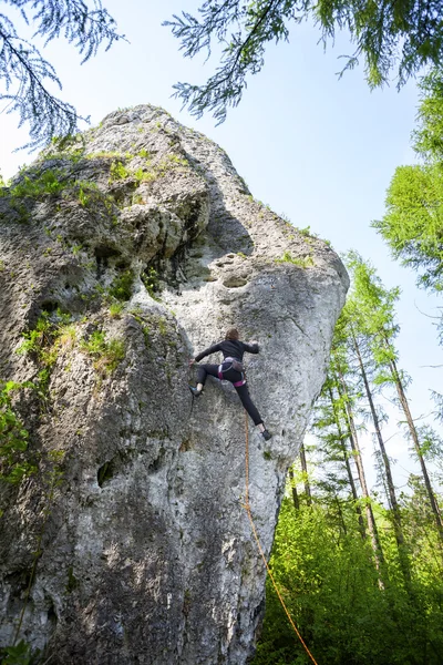 Jeune femme escalade difficile rocher dans la forêt . — Photo