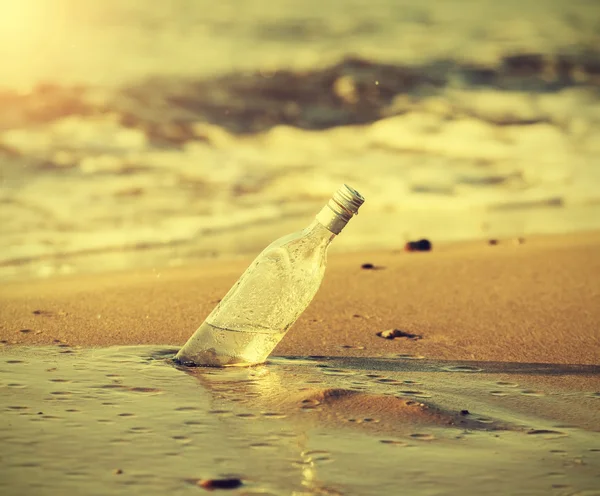 Bottle in water at sunset, retro instagram vintage effect. — Stock Photo, Image