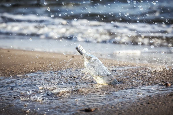 Bottle with water drops on beach. — Stock Photo, Image