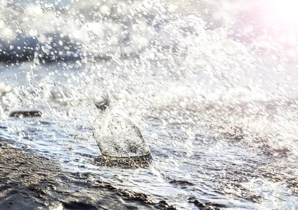 Garrafa com gotas de água na praia . — Fotografia de Stock