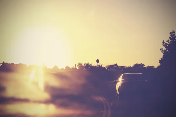 Вінтажне зображення дороги з машинами в русі проти сонця . — стокове фото