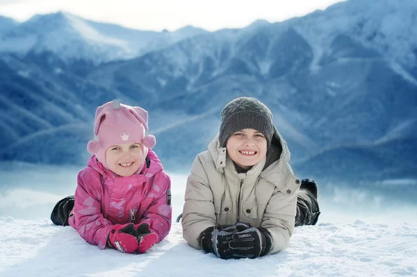 Girl and boy lie on the snow — Stock Photo, Image