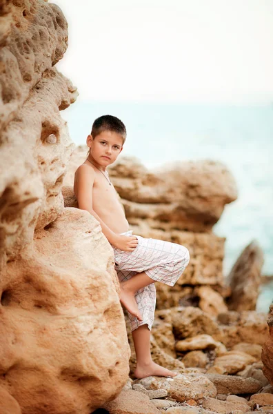 Boy stands near a rocky seashore — Stock Photo, Image