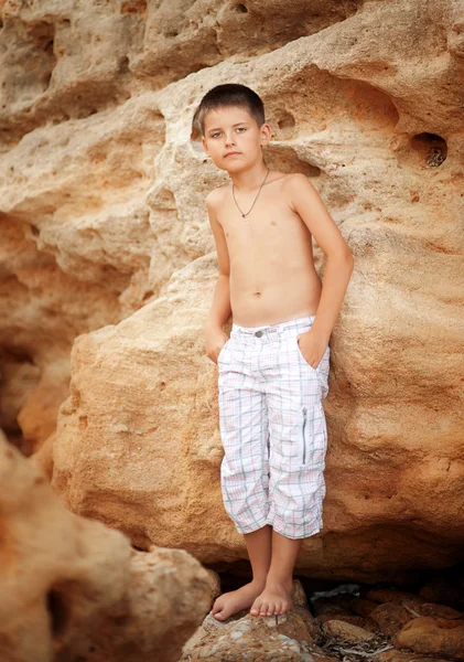 Boy stands near a rocky seashore — Stock Photo, Image