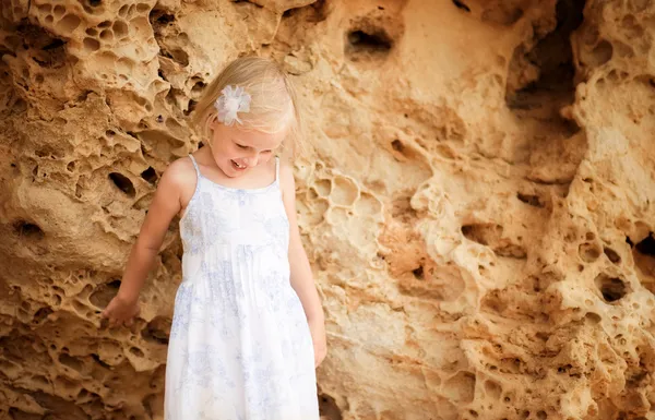 Маленька дівчинка виглядає біля скелі — стокове фото