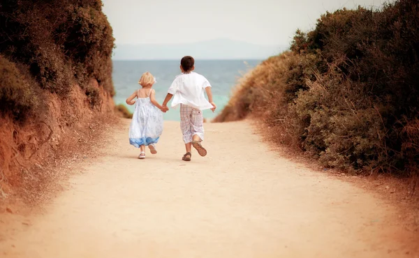 Boy and girl run on road to the sea — Stock Photo, Image