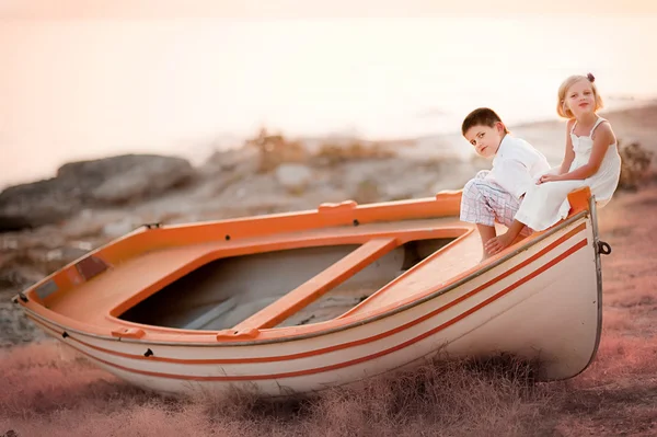 Mignon garçon et fille assis dans un bateau — Photo