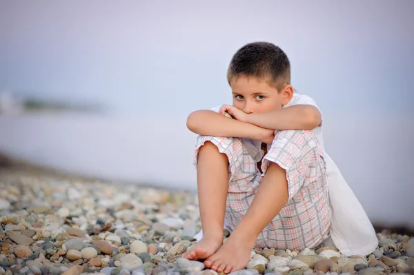 Menino senta-se em pedra seacoastby perto do mar — Fotografia de Stock