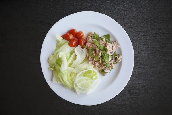 Fresh chopped tuna salad with spinach on black wood — Stock Photo, Image