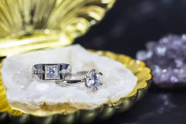 Designer wedding rings in the corner on a sparkling glitter background in panoramic banner format with copy space and selective focus