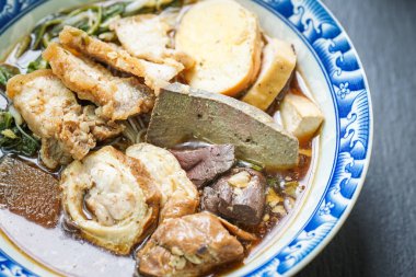 Beş baharatlı pirinçli erişte çorbası ahşap bir masada fayanslı bir kapta servis edilir..