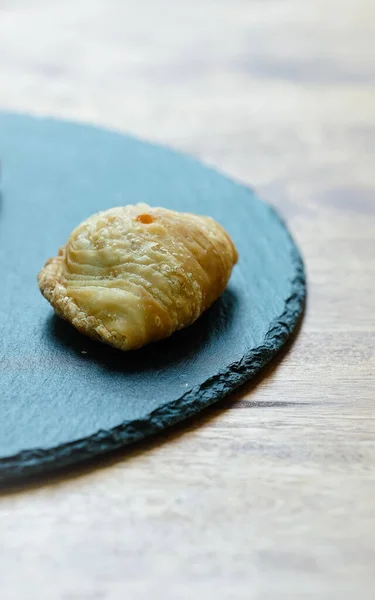 Curry puff pastry in a stone plate placed on a wooden table.