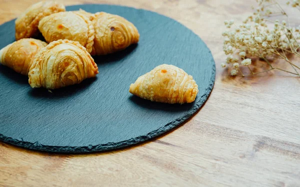 Curry puff pastry in a stone plate placed on a wooden table.