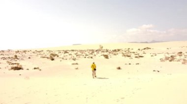 Kanarya Adaları, Fuerteventura 'daki Corralejo Parkı' nın kumullarında İHA uçuran genç bir adamın hava görüntüsü. İspanya