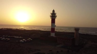 Gün batımında Toston deniz fenerinin havadan görünüşü, Punta Ballena, El Cotillo kasabası, Fuerteventura adası, Kanarya Adaları. İspanya, 4k video