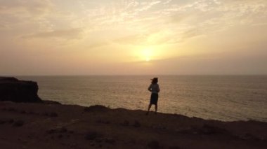 Fuerteventura, Kanarya Adaları 'nın kuzeyindeki El Cotillo kasabasında günbatımının keyfini çıkaran genç bir kadın. İspanya, 4k video