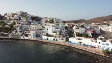 Sahilin ve Kanarya Adaları 'ndaki Fuerteventura adasının doğu kıyısındaki Las Playitas sahil kasabasının havadan görüntüsü. İspanya, 4k video