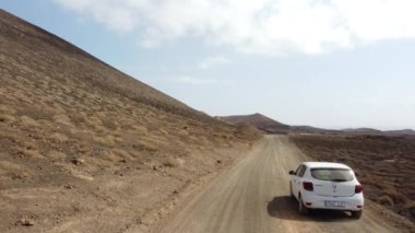 Kanarya Adaları, Fuerteventura adasının kuzey sahilindeki Corralejo 'daki Calderon Hondo volkanı yakınlarında bir arabanın hava aracı görüntüsü. İspanya
