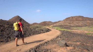 Sarı sırt çantalı genç bir adam kuzeye, Isla de Lobos 'a doğru gidiyor. Fuerteventura adasının kuzey kıyısı boyunca, Kanarya Adaları. İspanya