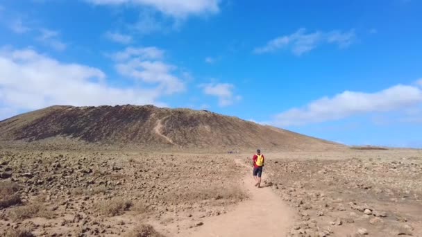 カナリア諸島フエルテベントゥラ島の北海岸 コラーレホ近くのカルデロン ホンド火山の火口へ向かう若い男のトレッキング スペイン — ストック動画